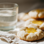 Freshly baked lemon curd cookies on a white napkin with a glass of water on a clean table